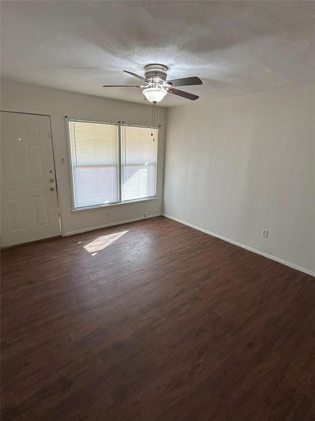 Living room with ceiling fan, a textured ceiling, 
