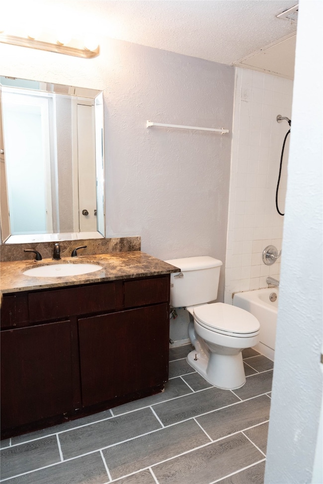 Full bath featuring a textured wall, vanity, bathtub / shower combination, wood tiled floors, and a textured ceiling