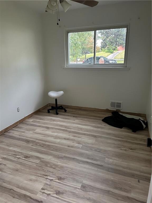 Unfurnished room with light wood-type flooring, ceiling fan, and a wealth of natural light