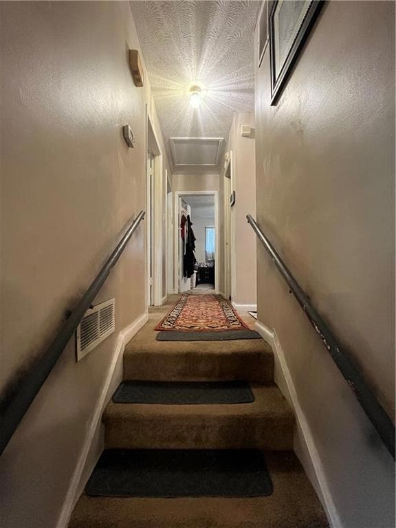 Staircase featuring a textured ceiling, baseboards