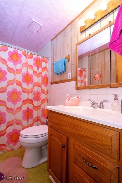 Bathroom featuring curtained shower, vanity, tile walls, and backsplash