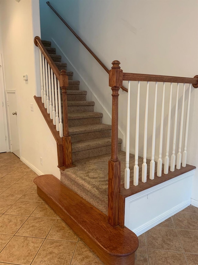 Stairway with tile patterned floors and baseboards