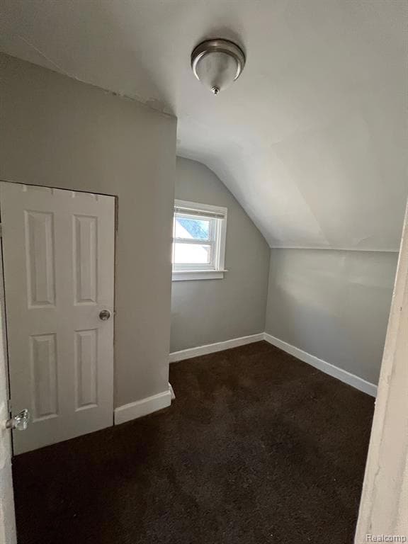 Bonus room featuring vaulted ceiling and dark colored carpet