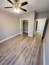 Unfurnished bedroom with ceiling fan, a closet, baseboards, and wood finished floors