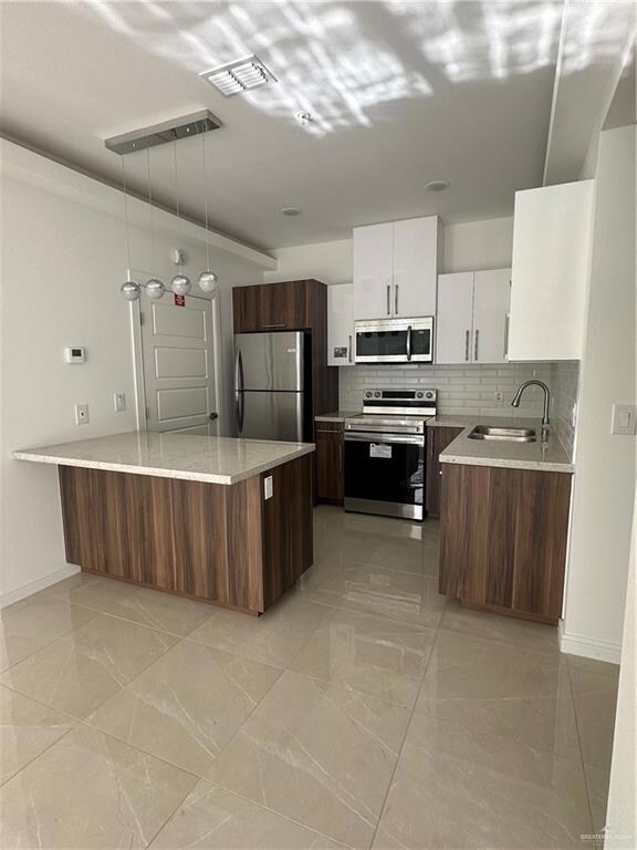Kitchen with visible vents, a sink, white cabinetry, fridge, and stove