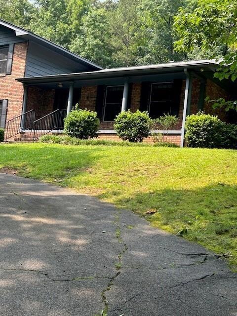 View of front facade featuring brick siding, covered porch, and a front lawn