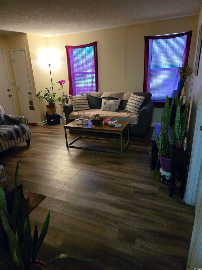 Living area with a textured ceiling, baseboards, a