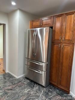 Kitchen with freestanding refrigerator, brown cabinets, and recessed lighting