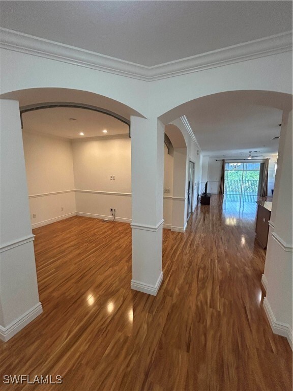 Hallway with arched walkways, crown molding, and w