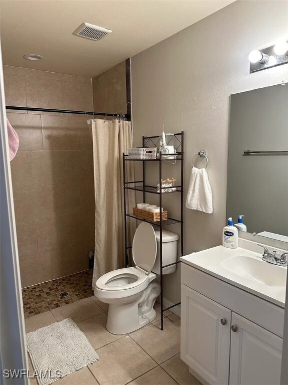 Bathroom with toilet, tiled shower, vanity, and ti