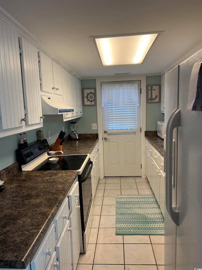 Kitchen with light tile patterned floors, refriger
