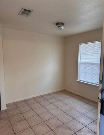Empty room featuring baseboards and light tile pat