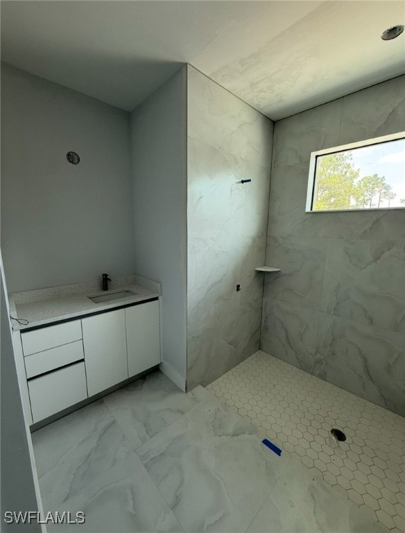 Full bath with vanity, marble look tiles, and tile