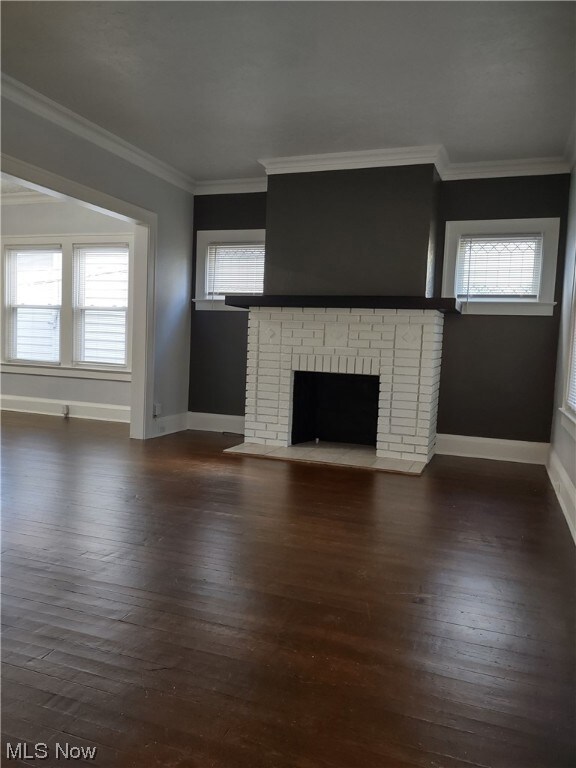 Unfurnished living room featuring a wealth of natural light, dark hardwood / wood-style floors, and a brick fireplace