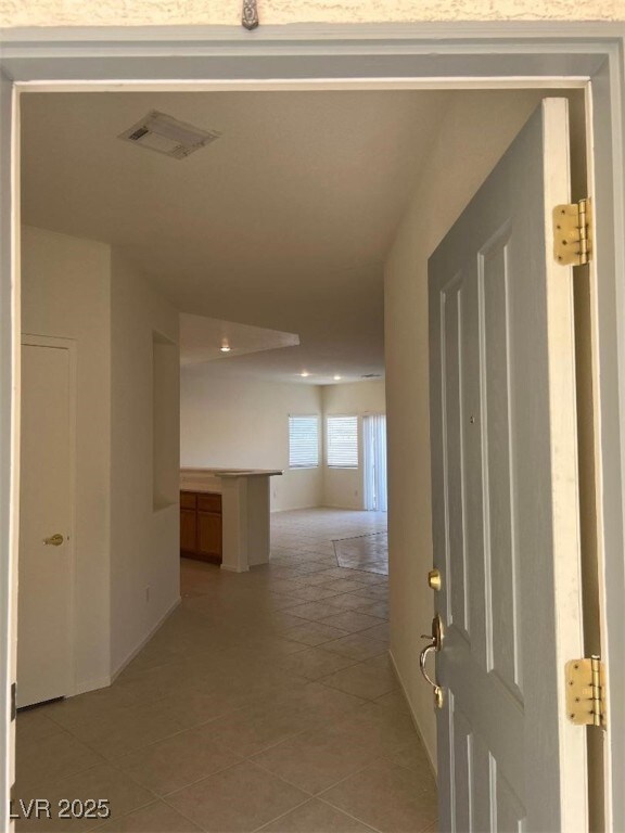Hallway with light tile patterned flooring and rec