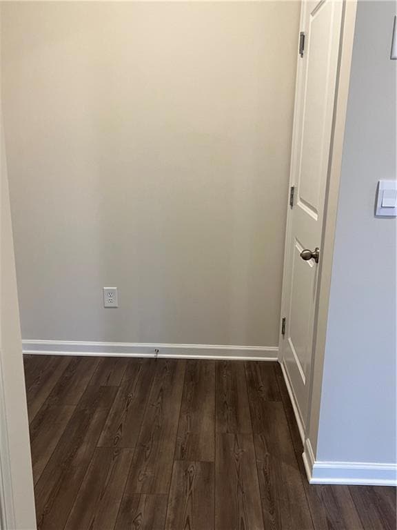 Unfurnished room featuring baseboards and dark wood-type flooring
