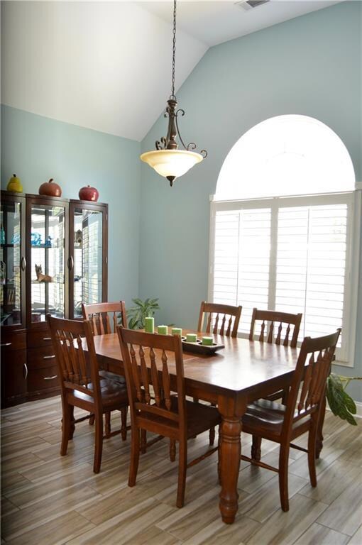 Dining area with visible vents, vaulted ceiling, a