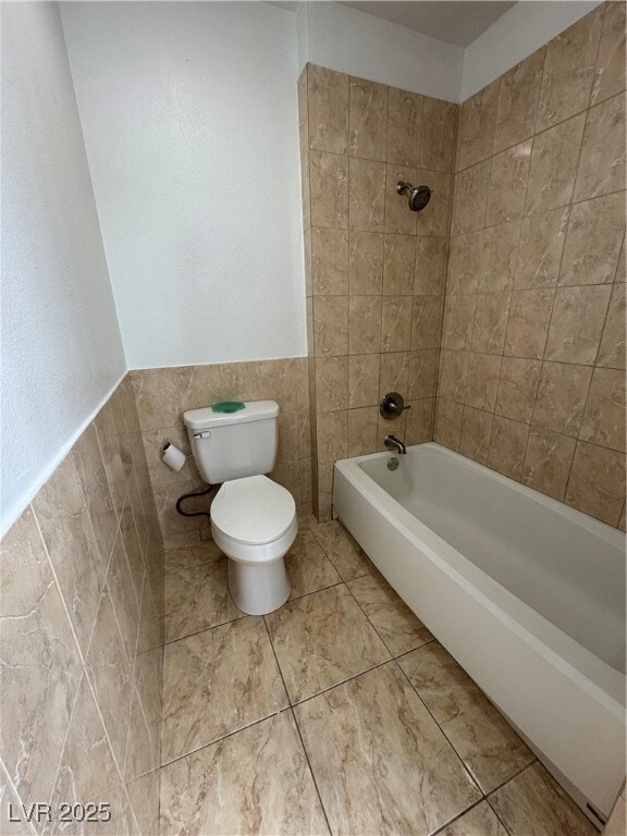 Full bathroom featuring tile walls, toilet, shower