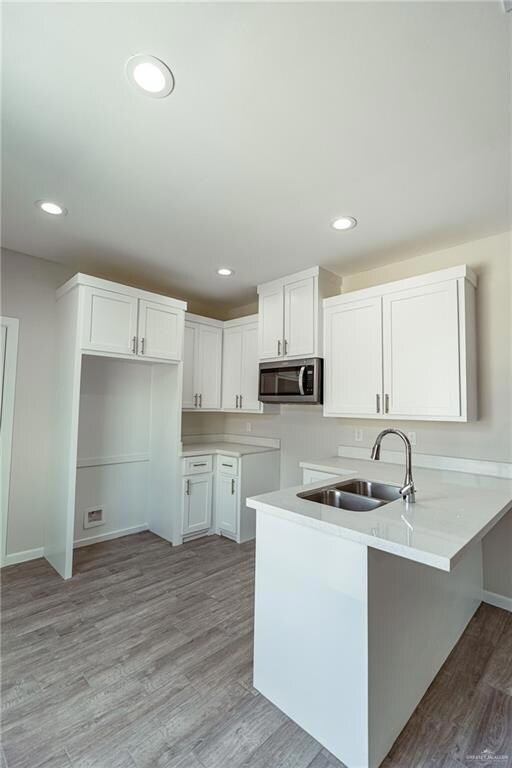 Kitchen with sink, white cabinets, light hardwood / wood-style floors, and kitchen peninsula