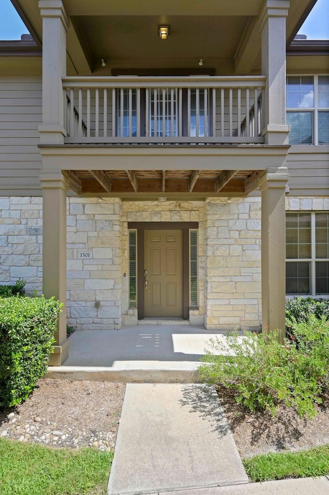 Property entrance with a balcony and stone siding