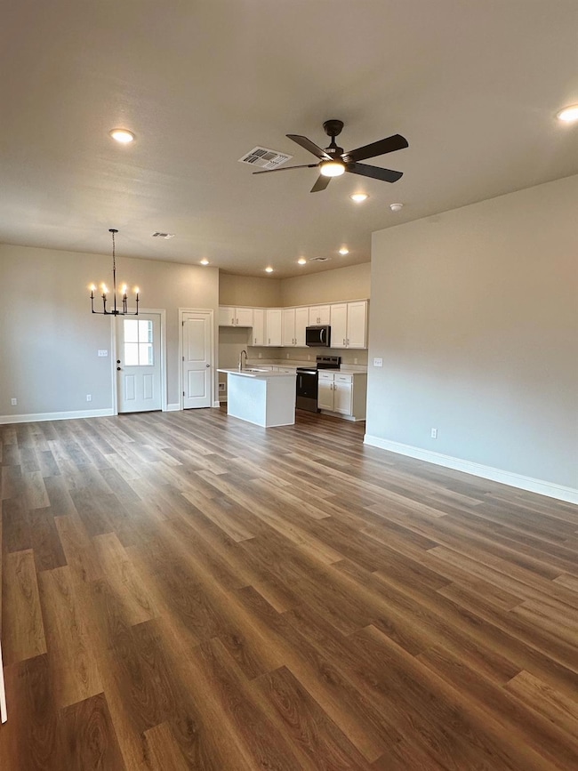 Unfurnished living room featuring sink, dark hardw