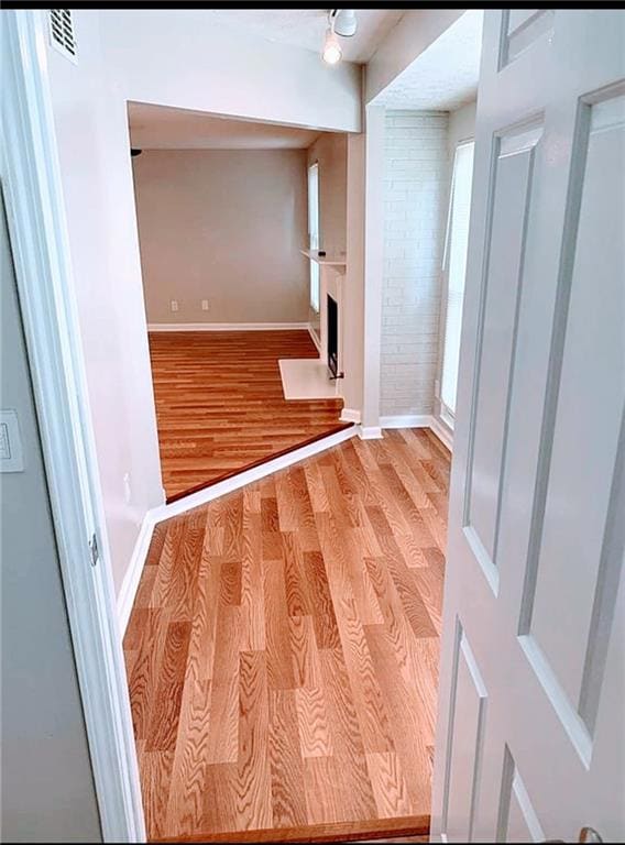 Hallway with light wood finished floors and brick wall