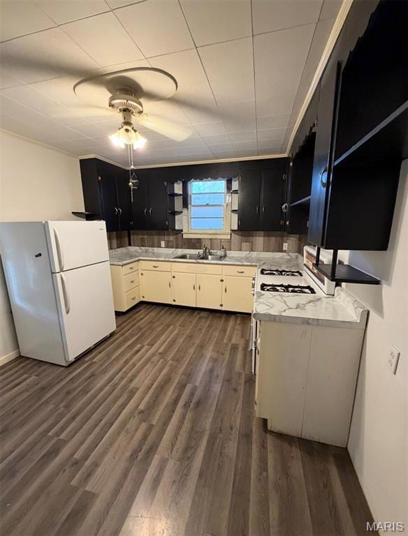 Kitchen with dark cabinetry, white appliances, light countertops, open shelves, and dark wood finished floors