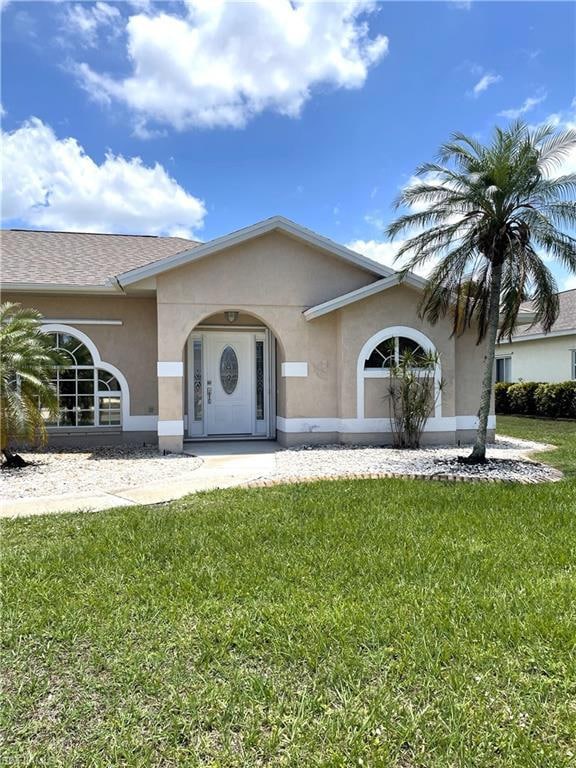 View of front facade with stucco siding and a front lawn