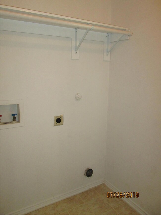 Washroom with hookup for an electric dryer, washer hookup, and light tile patterned floors