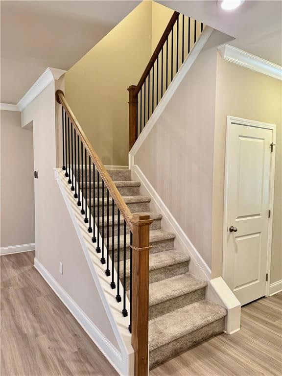 Stairway with baseboards, wood finished floors, an