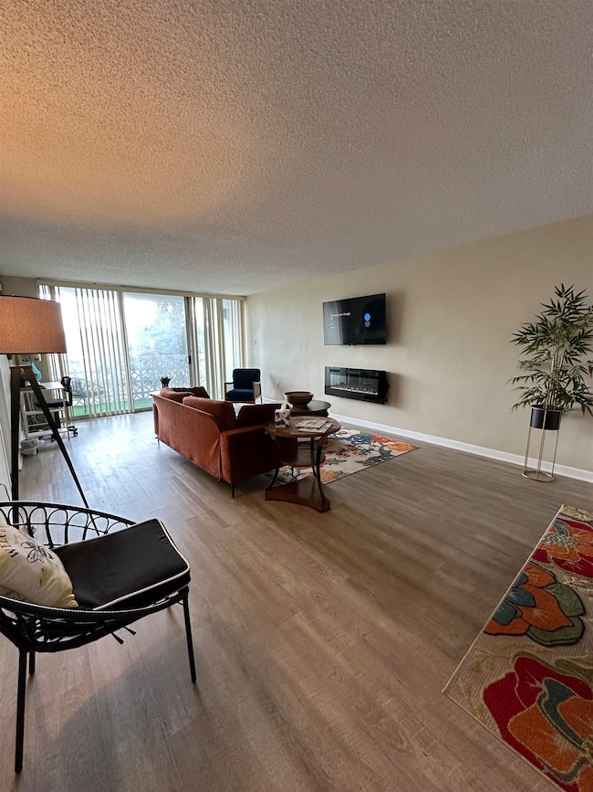 Living area featuring a textured ceiling, a wall of windows, and wood finished floors