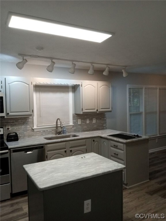 Kitchen with sink, backsplash, a kitchen island, stainless steel appliances, and track lighting