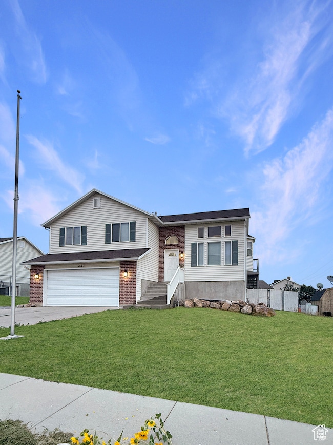 View of front facade featuring a garage, driveway, and brick siding