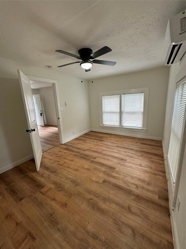 Bedroom featuring an AC wall unit, light wood-type