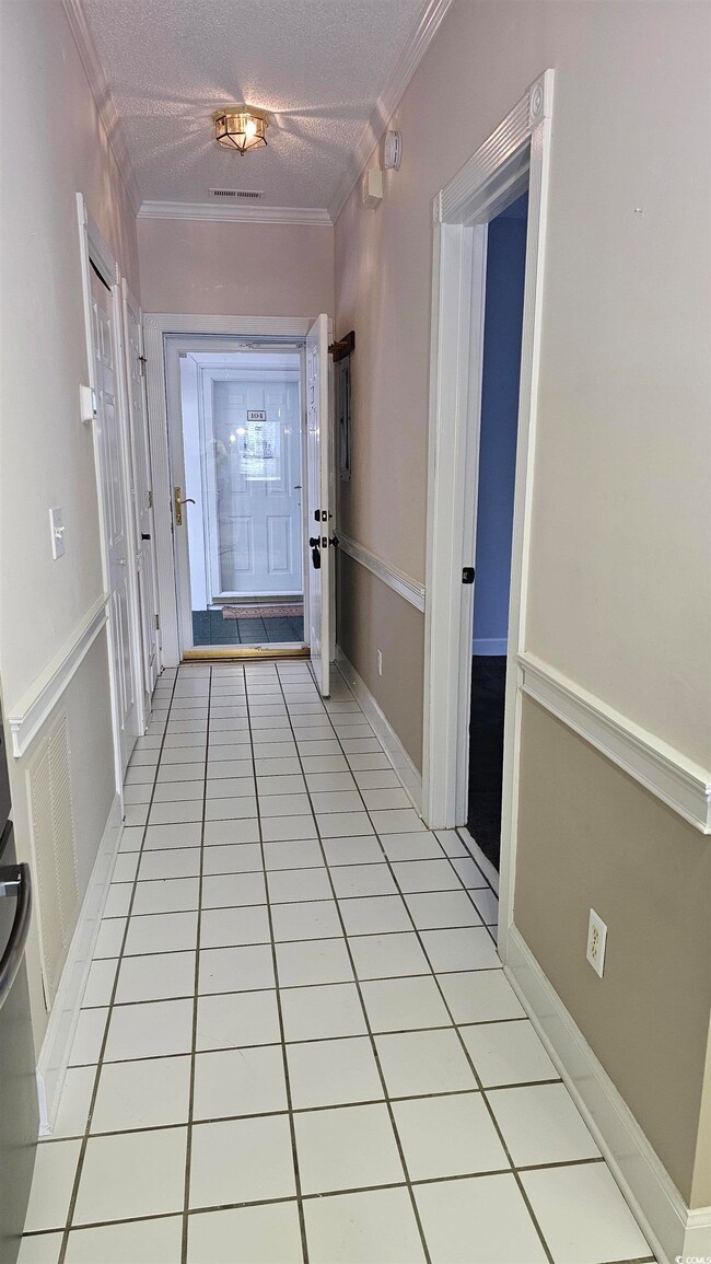 Hallway with a textured ceiling, light tile patter