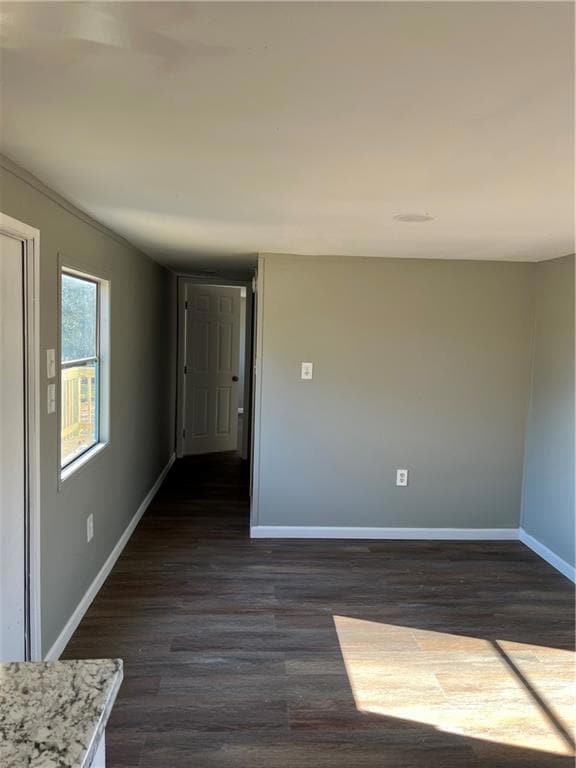Unfurnished room with dark wood-style floors and b
