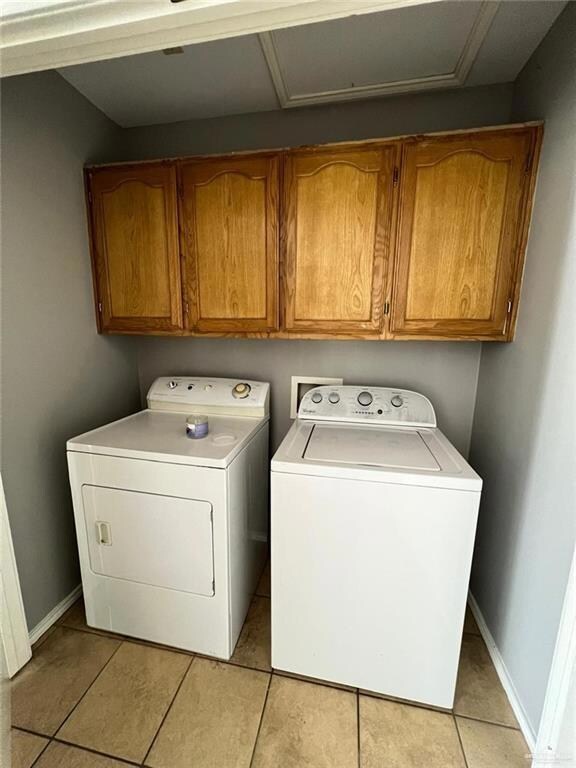 Laundry area with cabinet space, separate washer and dryer, light tile patterned floors, and attic access