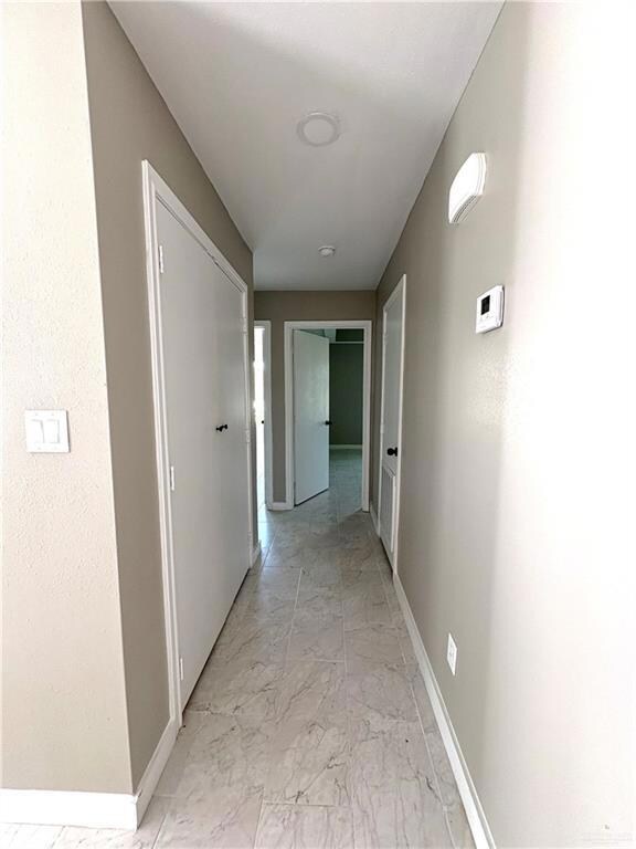 Hallway featuring light marble finish floors and baseboards
