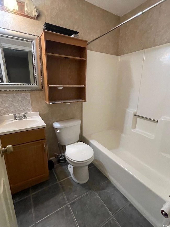 Full bathroom featuring toilet, tile patterned floors, vanity, and shower / washtub combination