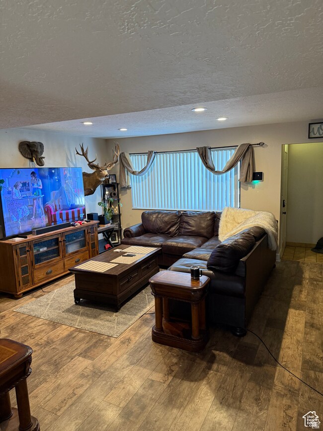 Living area featuring a textured ceiling, hardwood / wood-style flooring, and recessed lighting