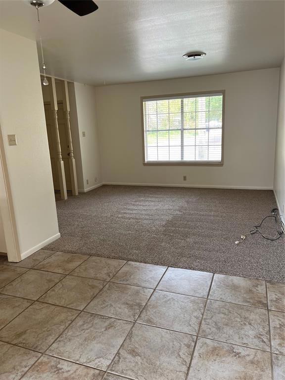 Tiled empty room featuring carpet and ceiling fan