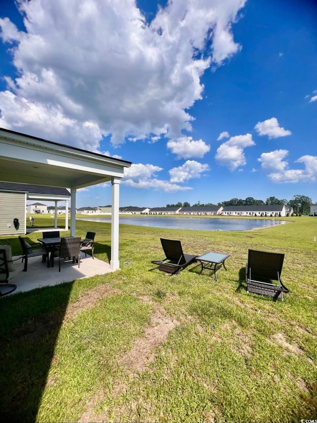 View of grassy yard with a water view and a patio area