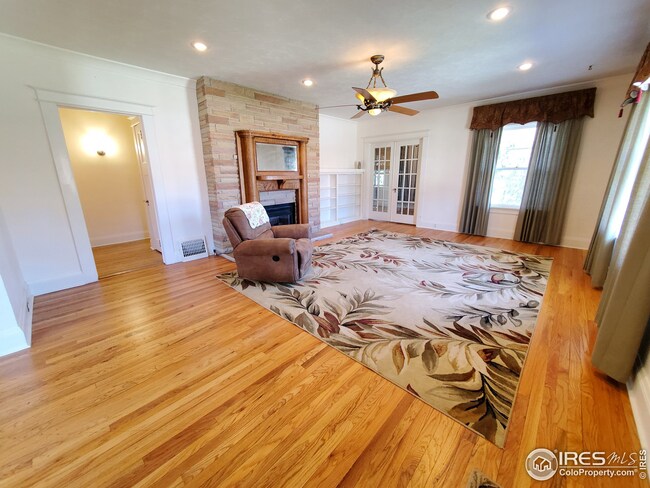 Welcoming living room boasts book shelves, natural light &  gas fireplace w/ oak mantel