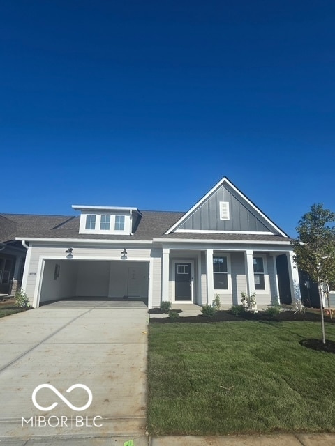 view of front facade with board and batten siding, driveway, a front yard, and a shingled roof