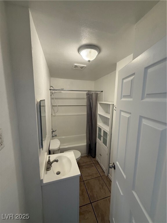 Bathroom featuring toilet, visible vents, tile pat