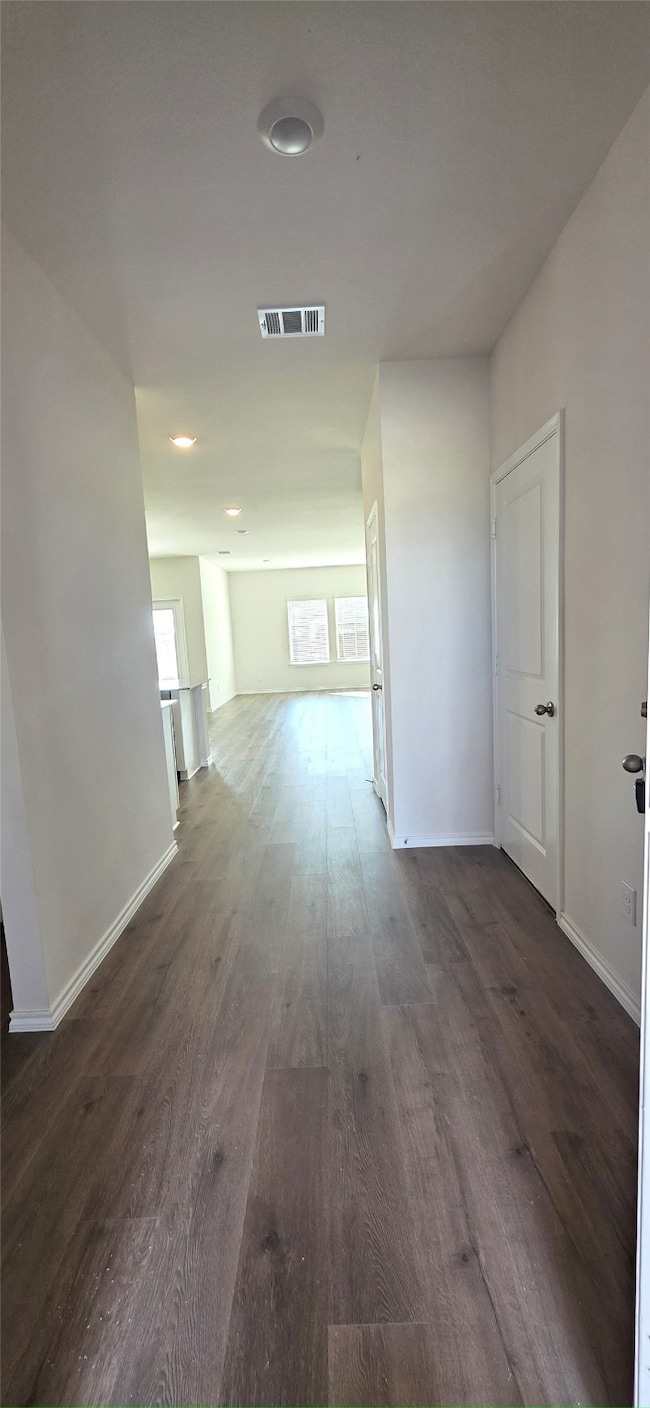 Corridor with dark wood-type flooring and baseboards