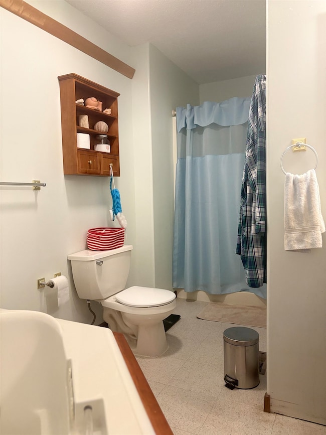 Bathroom featuring curtained shower and dark aggregate flooring