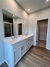 Full bathroom featuring double vanity, wood finished floors, a shower with door, and recessed lighting