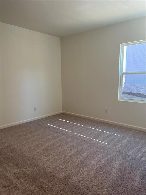 Carpeted empty room featuring baseboards