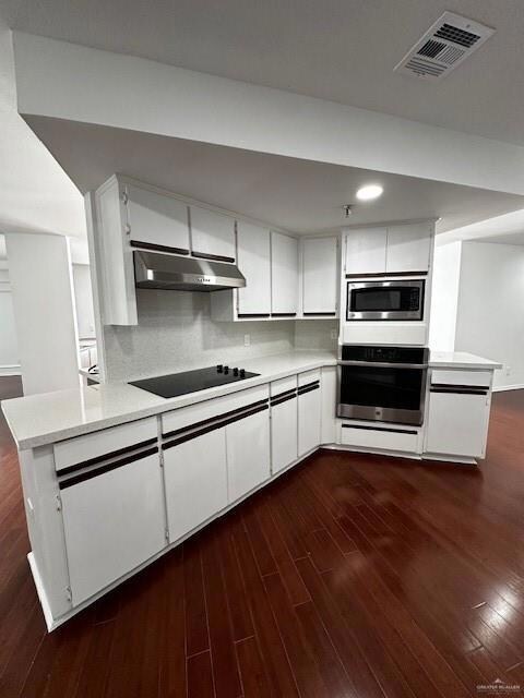 Kitchen with kitchen peninsula, oven, range hood, white cabinets, and dark hardwood / wood-style flooring